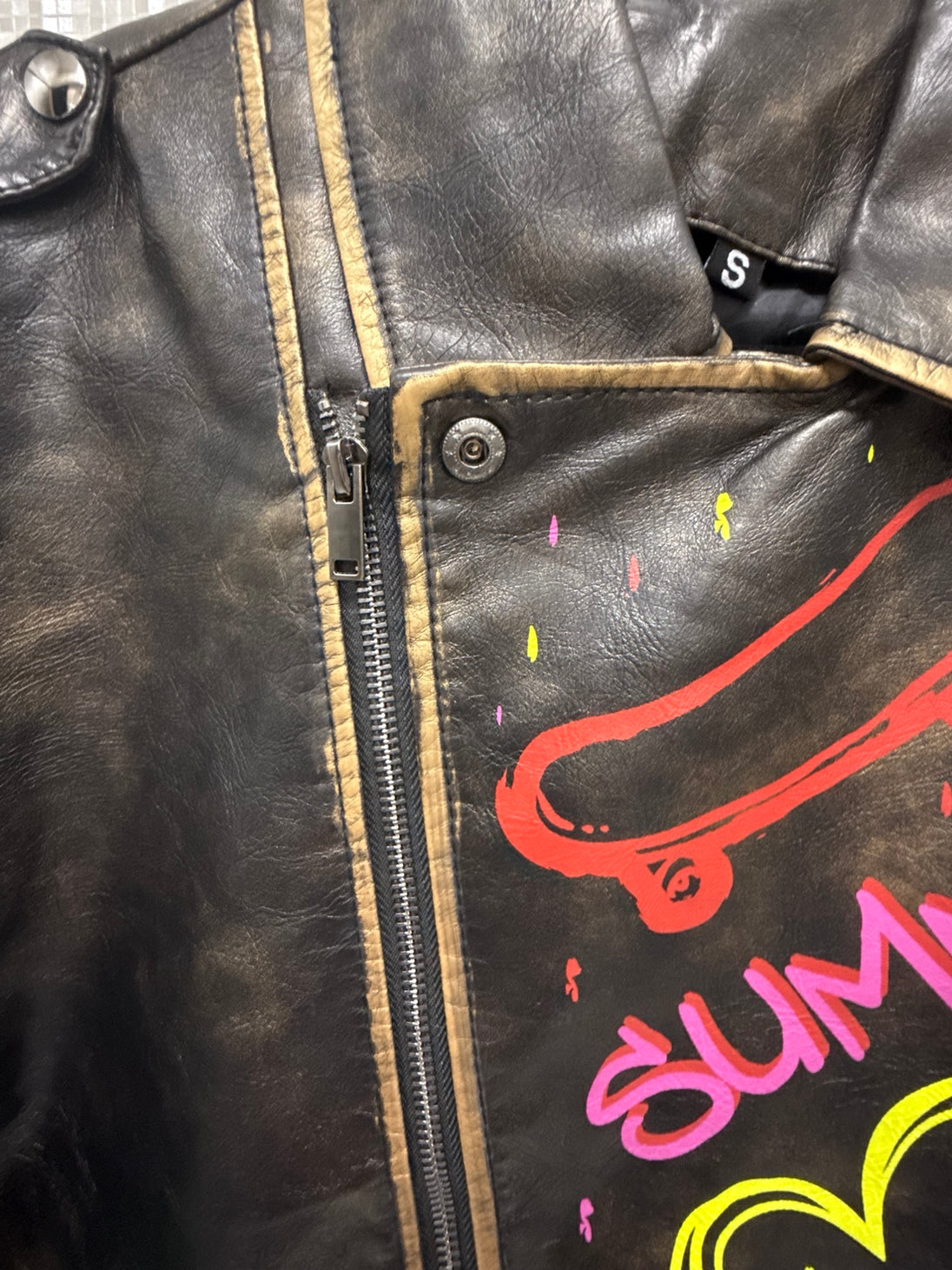 Black graffiti moto jacket zipper and distressed trim detail
